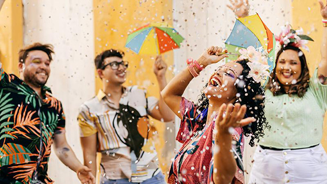 A diverse group of young adults celebrates outdoors. Confetti is falling on them.
