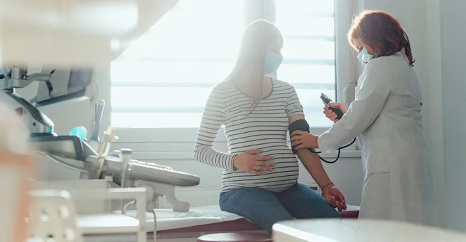 A pregnant woman gets her blood pressure checked in the exam room.