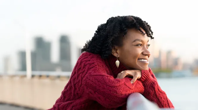 Woman looking over a bridge at the water and city