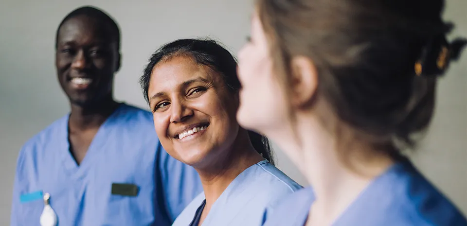 3 nurses are looking at each other and smiling.