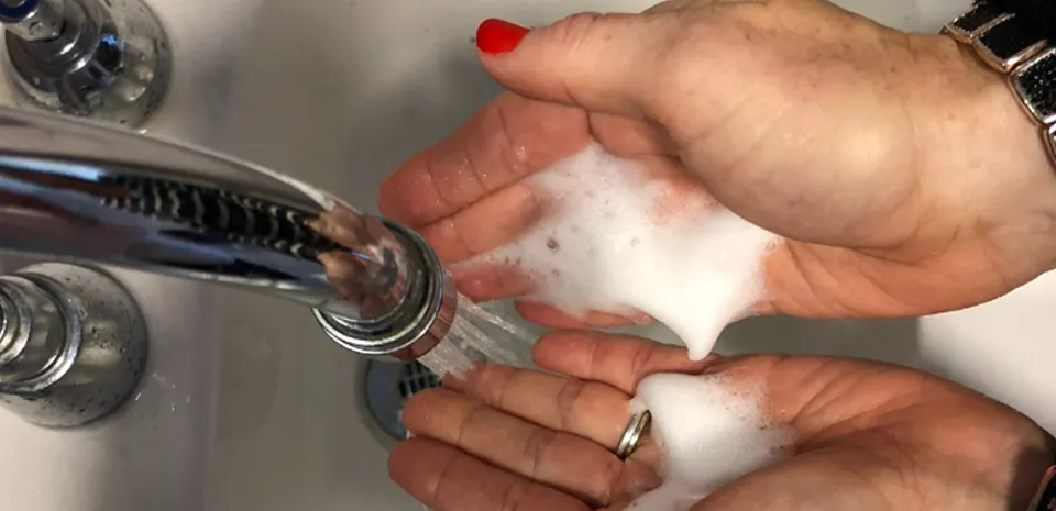 A close view of a woman's hands in a sink as she washes them