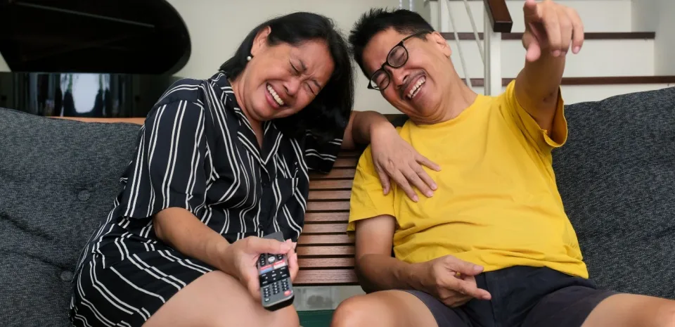 older couple watching TV and laughing which benefits heart health