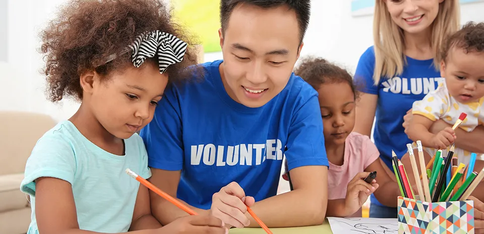 Volunteer Helping Child Draw