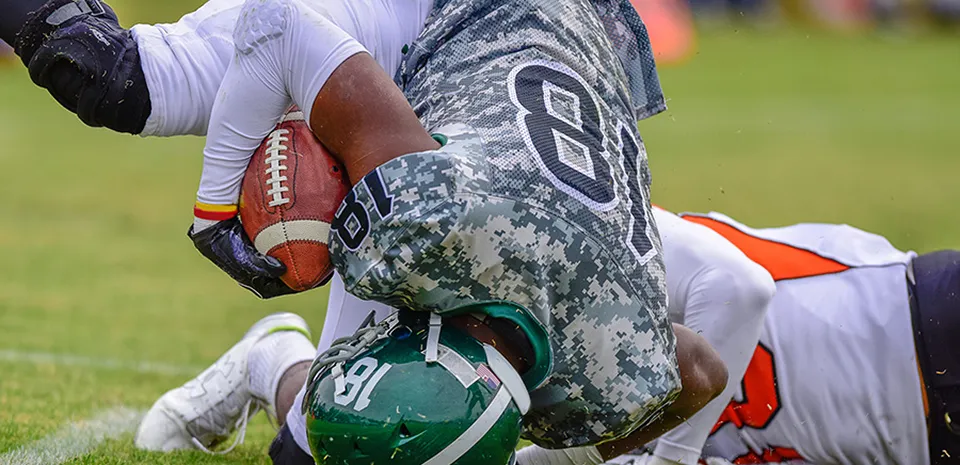 football players tackling one another while playing in a football game