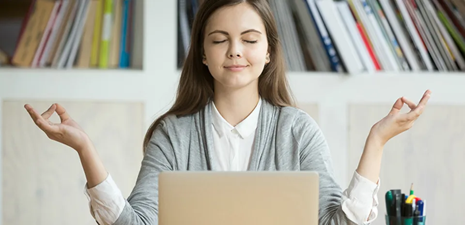 young woman mediating in front of laptop