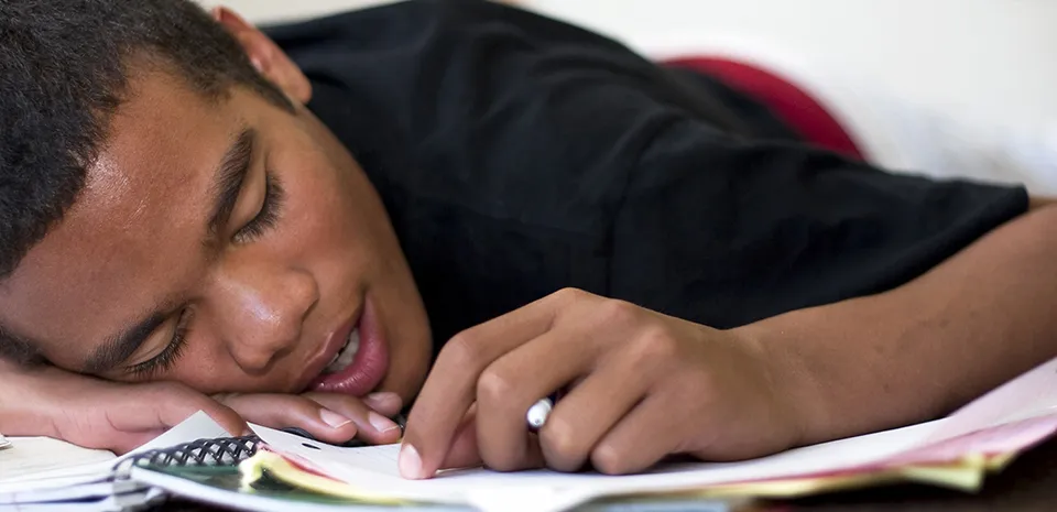 diverse teen falling asleep while doing homework