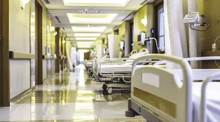 A hospital corridor with beds lining the right-hand wall.