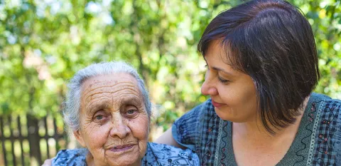 daughter looking and holding elderly mother