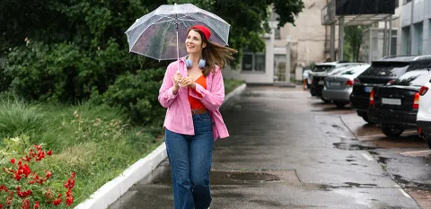 woman walking down the road with umbrella while it is raining