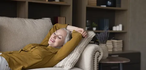 woman lying down and relaxing on living room couch