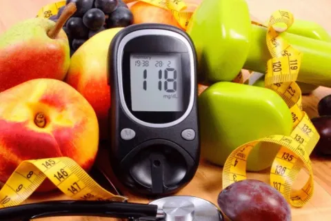 colorful fruits and veggies with a blood glucose monitor used to help achieve well controlled diabetes.