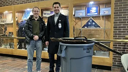 Physician Fred Schwartz and medical student Stanley Wojtas stand next to a trash bin with some of the guns people brought to the gun buyback.