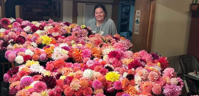 Sarah Skinner stands behind a table covered in dahlias of all different colors.