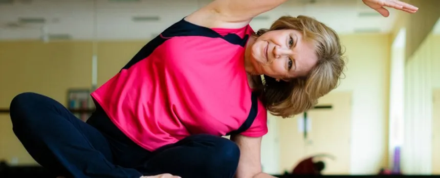 Woman sitting on a floor feeling the benefits of stretching
