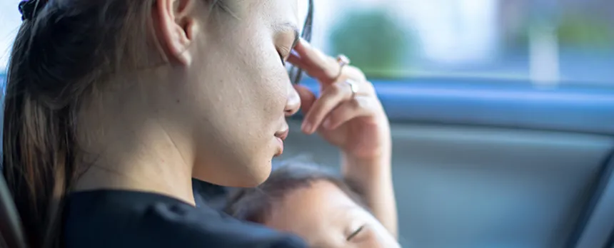 young mom experiencing postpartum depression while holding newborn baby