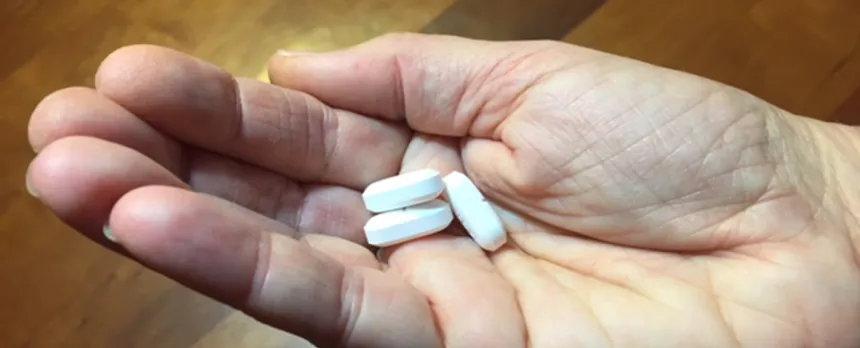 hand holding 3 white pills
