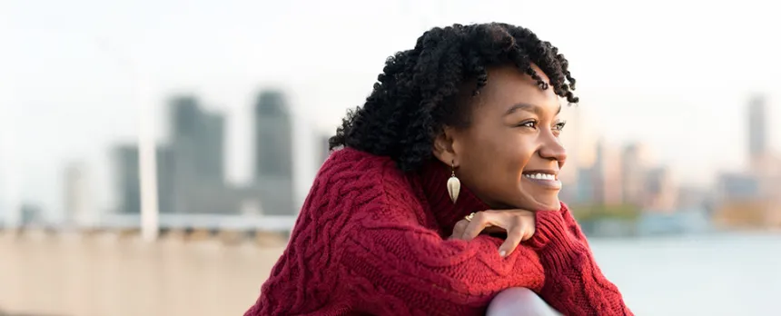 Woman looking over a bridge at the water and city
