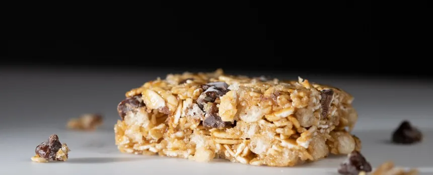 A closeup of a granola bar is shown against a black background.
